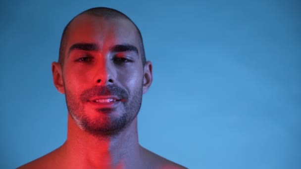 Close view of smiling fitness man, flexing chest and shoulders on blue background — Stock Video