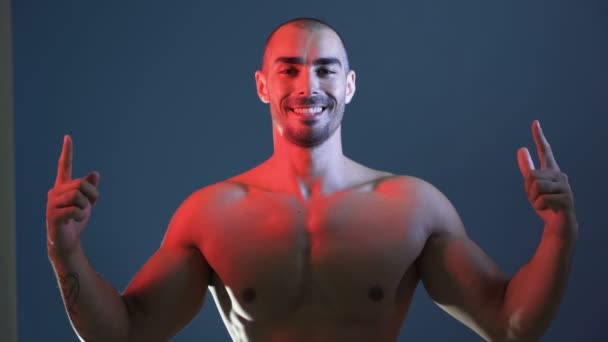 Θετικός αθλητικός άνδρας που δείχνει μυϊκό σώμα, λυγισμένα χέρια, στήθος και ώμους — Αρχείο Βίντεο