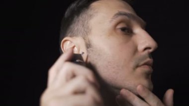 Sakal kesmek için tıraş bıçağı kullanan bir adamın profili. Siyah arkaplanda izole