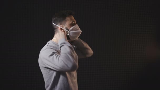 Jongeman met gezichtsmasker tegen zwarte achtergrond — Stockvideo