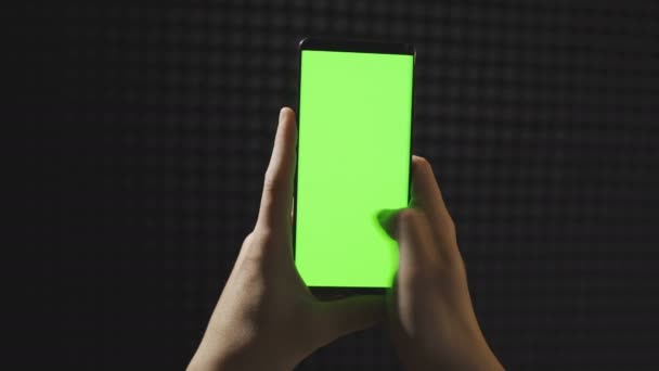 Mans hand scrollen smartphone met groen scherm geïsoleerd op zwarte achtergrond — Stockvideo