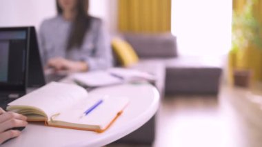 Ev ofisinden dizüstü bilgisayar kullanarak çalışan motive genç kız kardeşler.