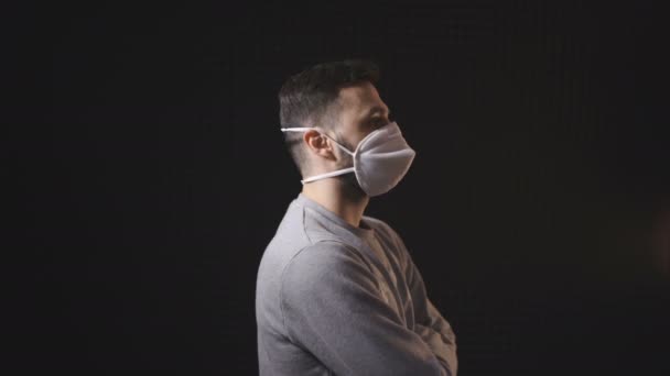 Seitenansicht des Mannes mit Gesichtsmaske zeigt mit dem Finger auf die Kamera, isoliert auf schwarzem Hintergrund — Stockvideo