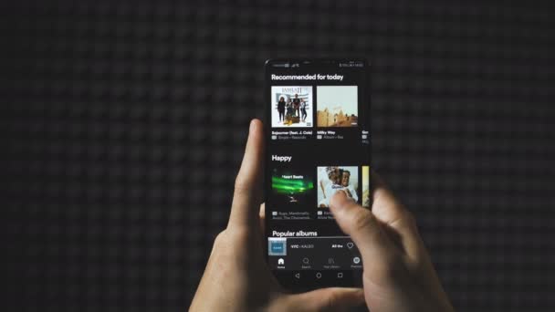 Sofya, Bulgaristan-25 05-2020: Akıllı telefon ekranında karanlık temalı Spotify 'da el kaydırması. Stüdyo çekimi — Stok video