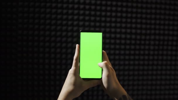Handscrollendes Smartphone mit grünem Bildschirm isoliert auf schwarzem Hintergrund