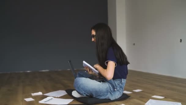 Женщина-фрилансер работает на полу с помощью ноутбука и ручки, чтобы делать заметки — стоковое видео