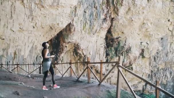 Vrouw in toeristische kleding verkennen enorme grot in Bulgarije. Grot van Devetashka bij Lovech, Bulgarije — Stockvideo
