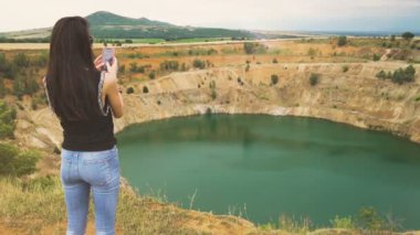 Bulgaristan 'da bakır madeni ocağının fotoğraflarını çekmek için akıllı telefonunu kullanan genç bir kadının arka plan görüntüsü