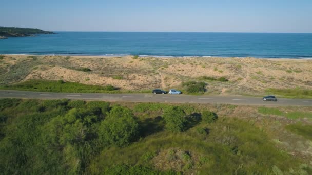 砂丘と穏やかな海を持つ美しい海の道の車に続くドローン — ストック動画