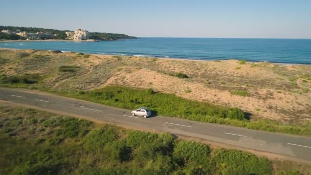 Srebrny samochód jadący wzdłuż wybrzeża w Alepu, Bułgaria. Drone następujące samochód jazdy powoli w pobliżu plaży, Morze Czarne — Wideo stockowe