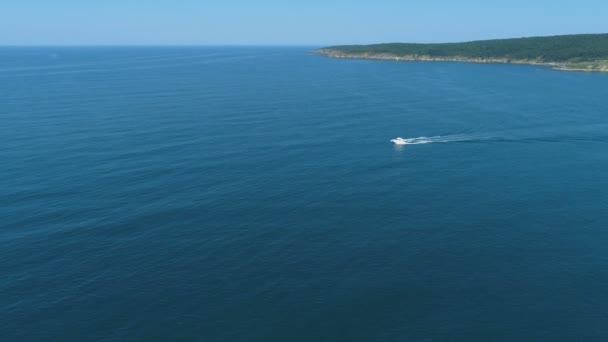 Bateau blanc flottant rapidement sur la surface de l'eau calme et laissant un sentier sur la mer