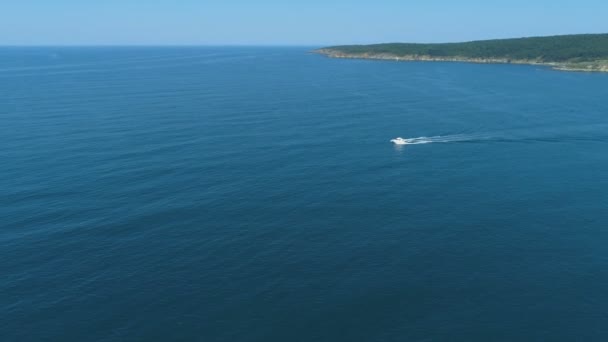 Barco blanco flotando rápidamente en la superficie del agua tranquila y dejando un rastro en el mar — Vídeo de stock