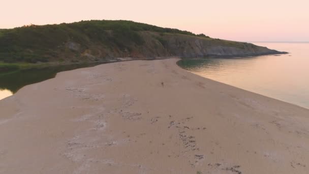 Paar spaziert auf schmalen Sandstreifen zwischen Fluss und Meer bei Sonnenuntergang in Sinemorets, Bulgarien — Stockvideo