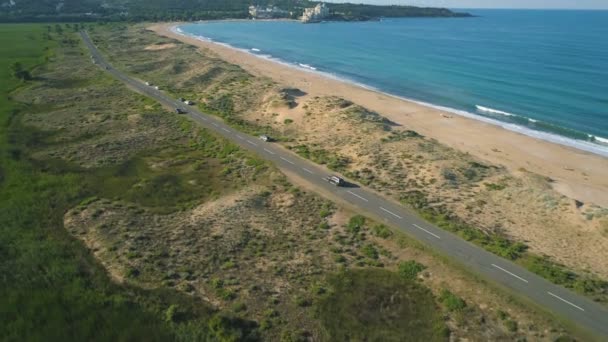 Kum plajı yakınlarındaki bir sahil yolundan giderek sahil şeridini keşfeden bir arabanın arkasında uçmak. Alepu, Bulgaristan — Stok video