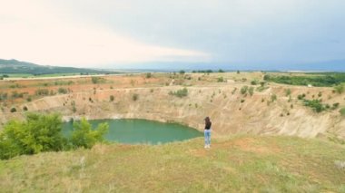 Terk edilmiş bakır madeninin kenarında yalnız bir kadın kamerayla fotoğraf çekiyor.