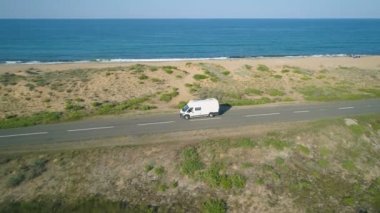 Güneşli bir günde güzel deniz yolu boyunca giden beyaz otobüsün yan görüntüsü. Alepu, Bulgaristan