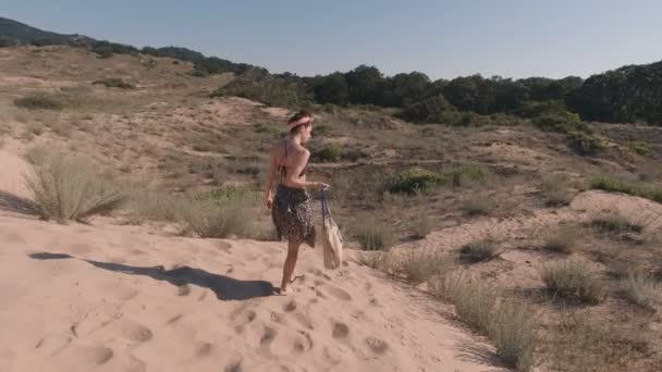 Suit jeune femme marchant sur la plage de sable portant sac de plage — Video