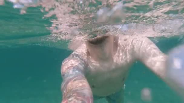 Turkuaz deniz suyunda yüzen genç aktif adam. — Stok video