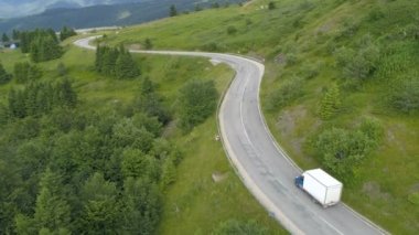 Dağ yolunda giden beyaz bir kamyonet ya da minibüs. Lojistik nakliye kamyonu kargo teslimatı