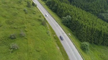 Bulutlu bir günde dağ yolunda giden arabalar. Turistler kampa gider, yaz tatillerinde trafik olur.