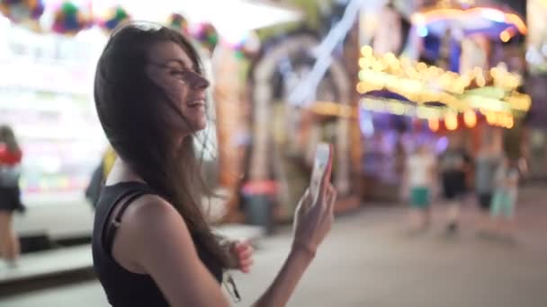 Heureuse femme souriante utilisant un smartphone pour filmer différentes manèges et attractions — Video