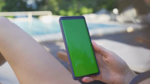 Žena ruka pomocí smartphone se zelenou obrazovkou na bazénu venku — Stock video