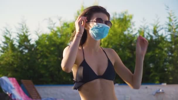 Fiatal nő fekete bikini felső és arc maszk rögzíti a napszemüveg — Stock videók