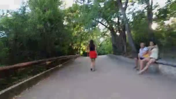 Varna, Bulgarien - 09 08 2020: Hyperlapse av en ung kvinna med klarröd kjol promenader i Varna Sea Garden park — Stockvideo
