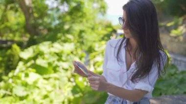 Beyaz gömlekli, güneş gözlüklü, elinde turist haritası olan güzel bir turist kız.