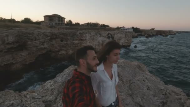 Romantic couple holding hands at the edge of rocky seashore. Kissing and hugging happy together — Stock Video
