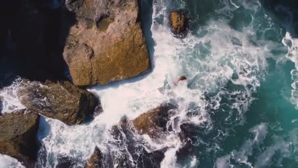 Drone vista superior de ondas furiosas colidindo com grandes rochas na costa búlgara em dia ensolarado — Vídeo de Stock