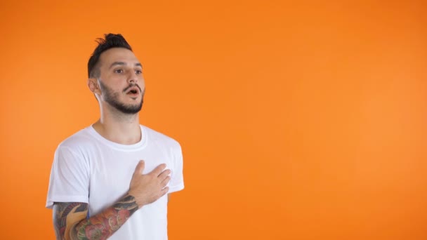 Junger Mann in Fußballuniform singt vor orangefarbenem Hintergrund eine Hymne — Stockvideo