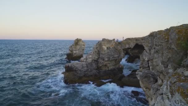 Vista aérea de ondas furiosas colidindo na formação de arco de rocha e caverna na costa marítima rochosa perto da aldeia de Tyulenovo, na Bulgária — Vídeo de Stock