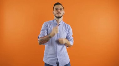 Gömlekli genç adam mutlu bir şekilde dans ediyor parmaklarını şaklatıyor ve kollarını sallıyor. Mutlu, pozitif erkek dans konsepti