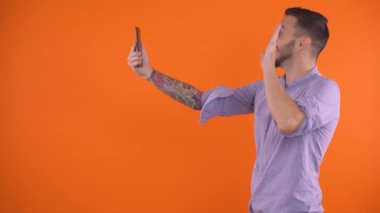 Heyecanlı genç adam videosu arıyor, gülümsüyor ve el sallıyor. Video çağrısı konseptiyle seni seviyorum demek.
