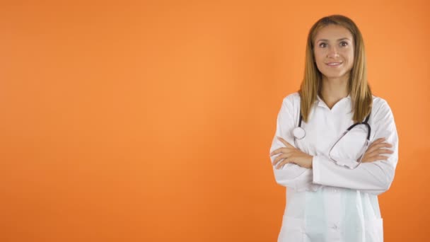女性医師がカメラの前で笑顔。オレンジスタジオの背景コピースペースのコンセプト — ストック動画