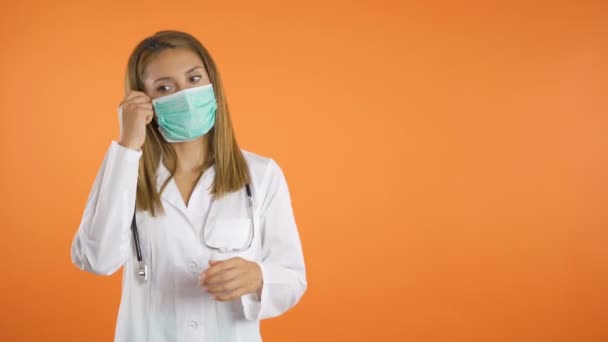 Ung vacker kvinnlig läkare tar av kirurgisk ansiktsmask och andas djupt och långsamt — Stockvideo