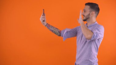 Kolunda dövmesi olan bir adam akıllı telefon kullanarak bir arkadaşını arıyor, stüdyo fotoğrafı.
