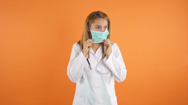 Jovem bonito médico feminino colocando em máscara cirúrgica — Vídeo de Stock