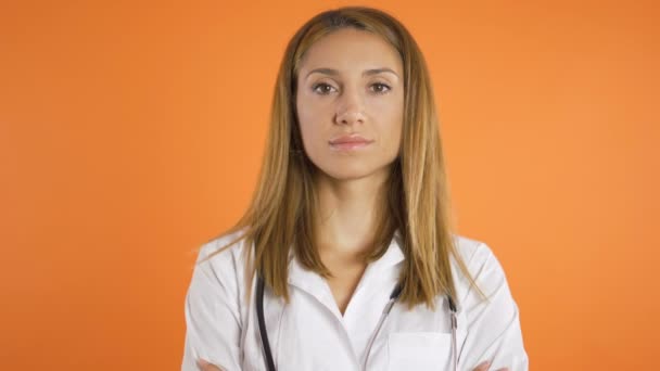 Porträtt av ung vacker kvinnlig läkare, närbild. Isolerad på orange bakgrund, studio skott — Stockvideo