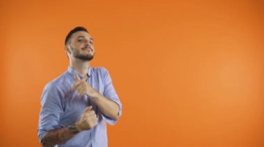 Neşeli genç adam, parmaklarıyla gösterip yavaşça dans ediyor.