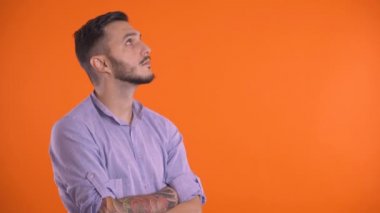 Yüzünde ya da çenesinde parmak olan düşünceli bir adam, turuncu arka planda soyutlanmış..