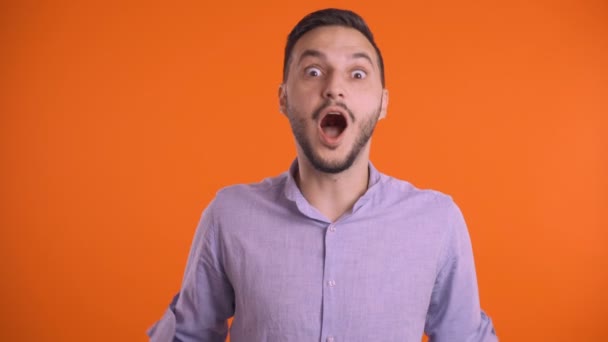 Jeune homme excité touchant la tête avec les mains sur fond de studio orange — Video