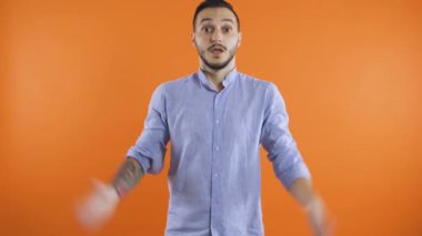 Kızgın, sinirli, elleri açık bağıran, turuncu arka planda soyutlanmış bir adam.