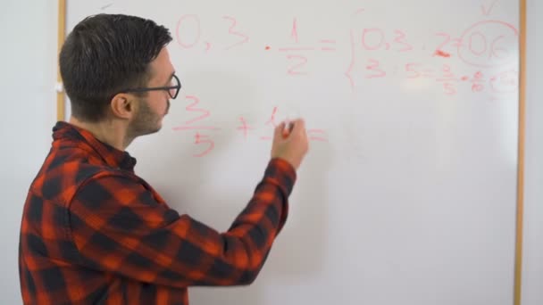 Kırmızı gömlekli ve gözlüklü genç öğretmen uzaktan matematik öğretiyor. — Stok video