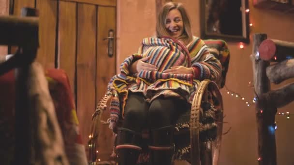 Femme enceinte souriante dans une chaise devant une petite maison confortable à Noël — Video