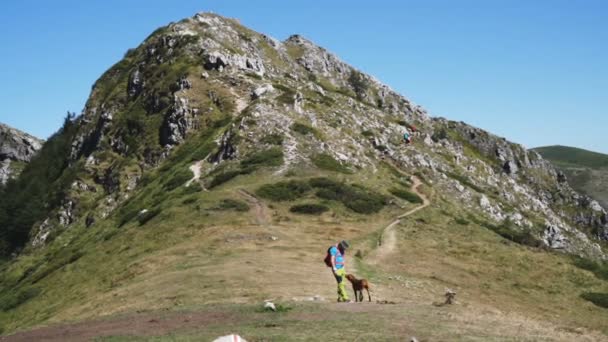 Jovem e seu cachorro em caminhadas de aventura nas montanhas — Vídeo de Stock