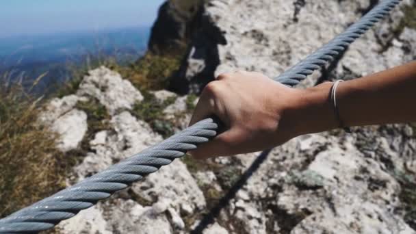 Mão feminina segurando corda de arame de aço apertado de uma ponte alta nas montanhas — Vídeo de Stock