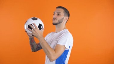 Beyaz mavi gömlekli kendine güvenen futbolcu hava topu atıyor.