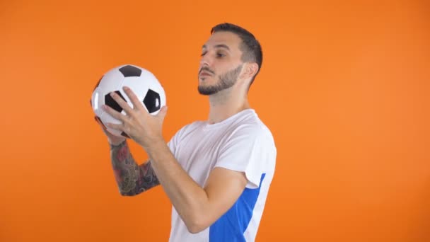 Gelukkig zelfverzekerde voetballer in wit blauw shirt gooien in lucht voetbal — Stockvideo